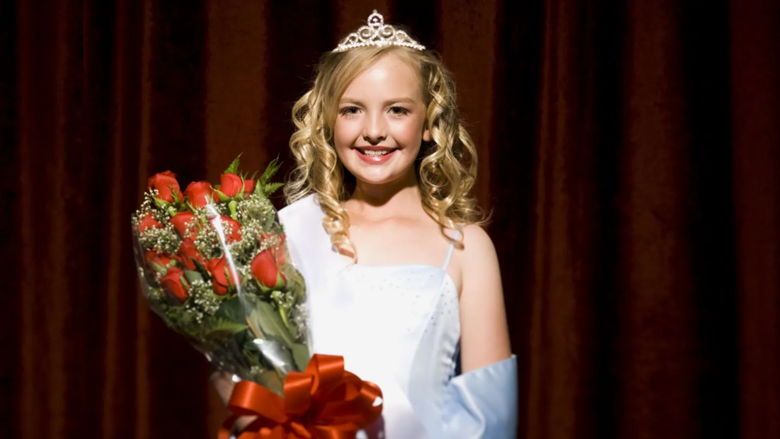 Half length of a beauty pageant winner smiling and holding roses