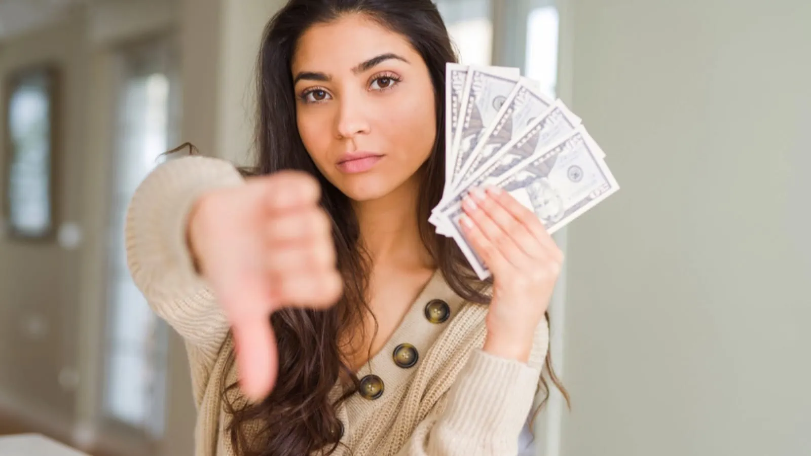 Woman with money showing thumbs down