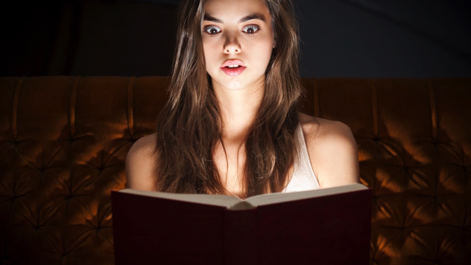 Beautiful girl reading book at night