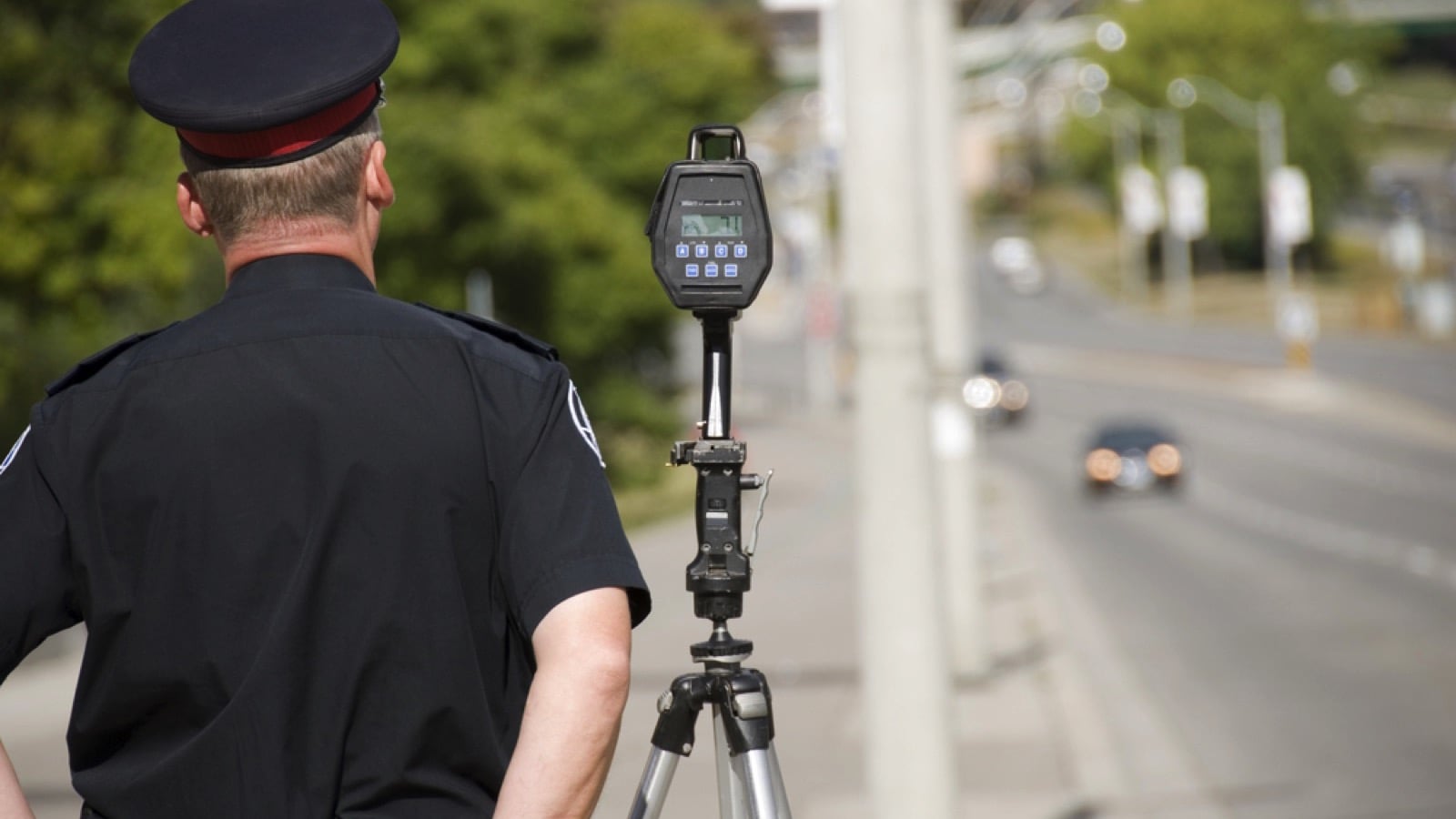 North American policeman waits to catch speeding drivers with a radar gun
