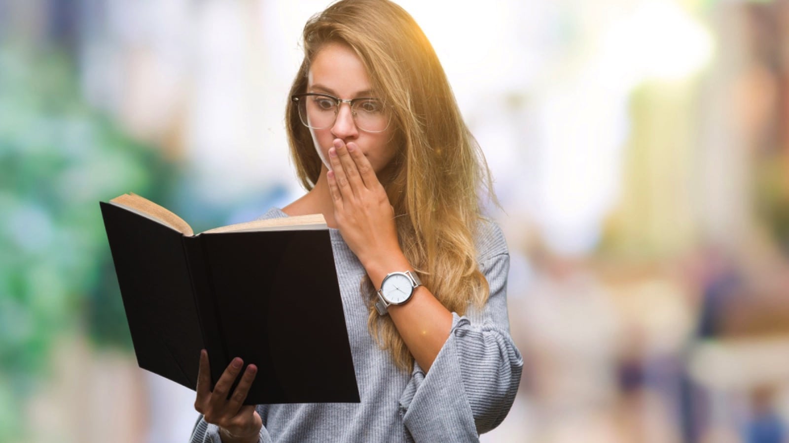 Woman reading book scared closing mouth